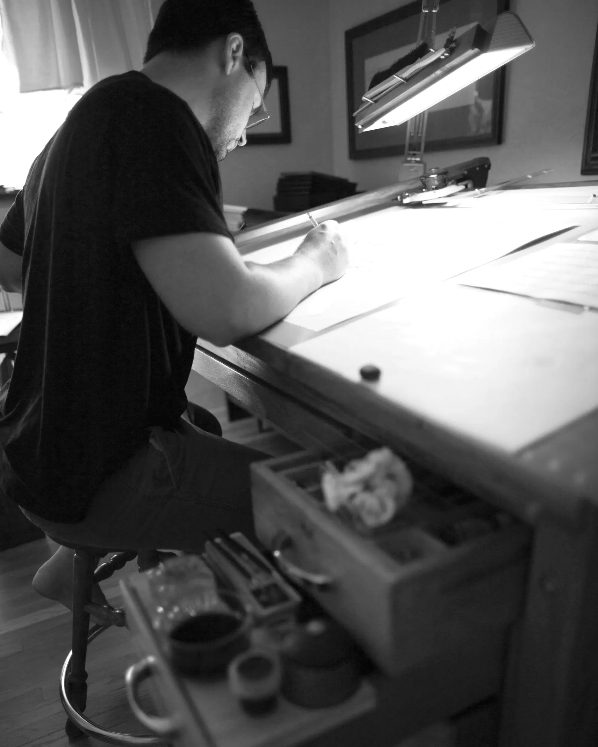 David Grimes working on a piece of calligraphy at the desk in his Portland studio.